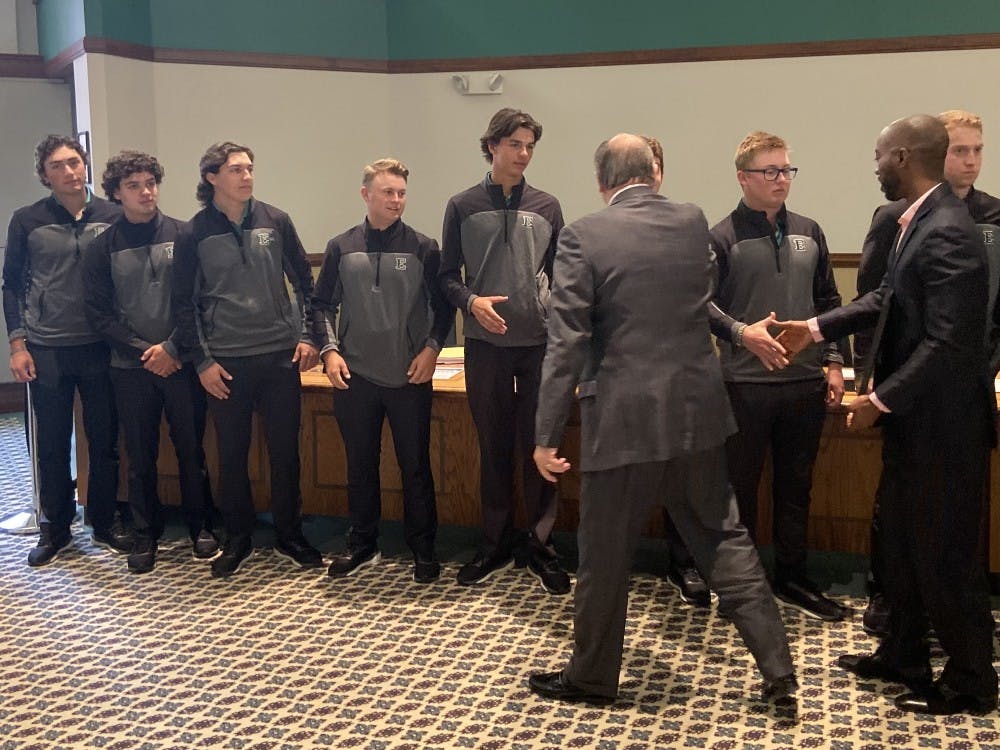 Smith and Simpson shake hands with student athletes