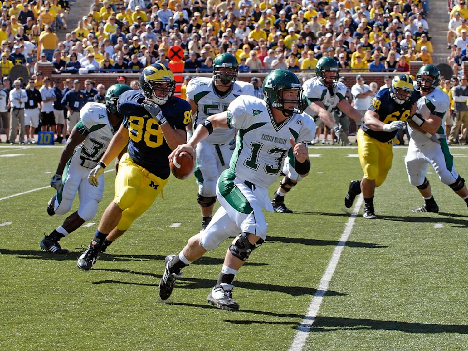 	Alex Gillett (13) under pressure from linebacker (88) Craig Roh during EMU’s 45-17 loss to Michigan on Sept. 19 when he filled in for the injured Andy Schmitt. Gillett will share playing time with Kyle McMahon on Saturday, coach Ron English said.