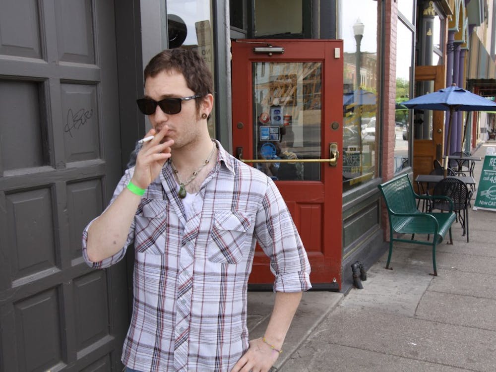 Junior Aaron Gunsberg lights up a cigarette outside of Sidetracks Bar and Grill, where he now has to smoke outside. The law bans smoking in bars, restaurants and business.