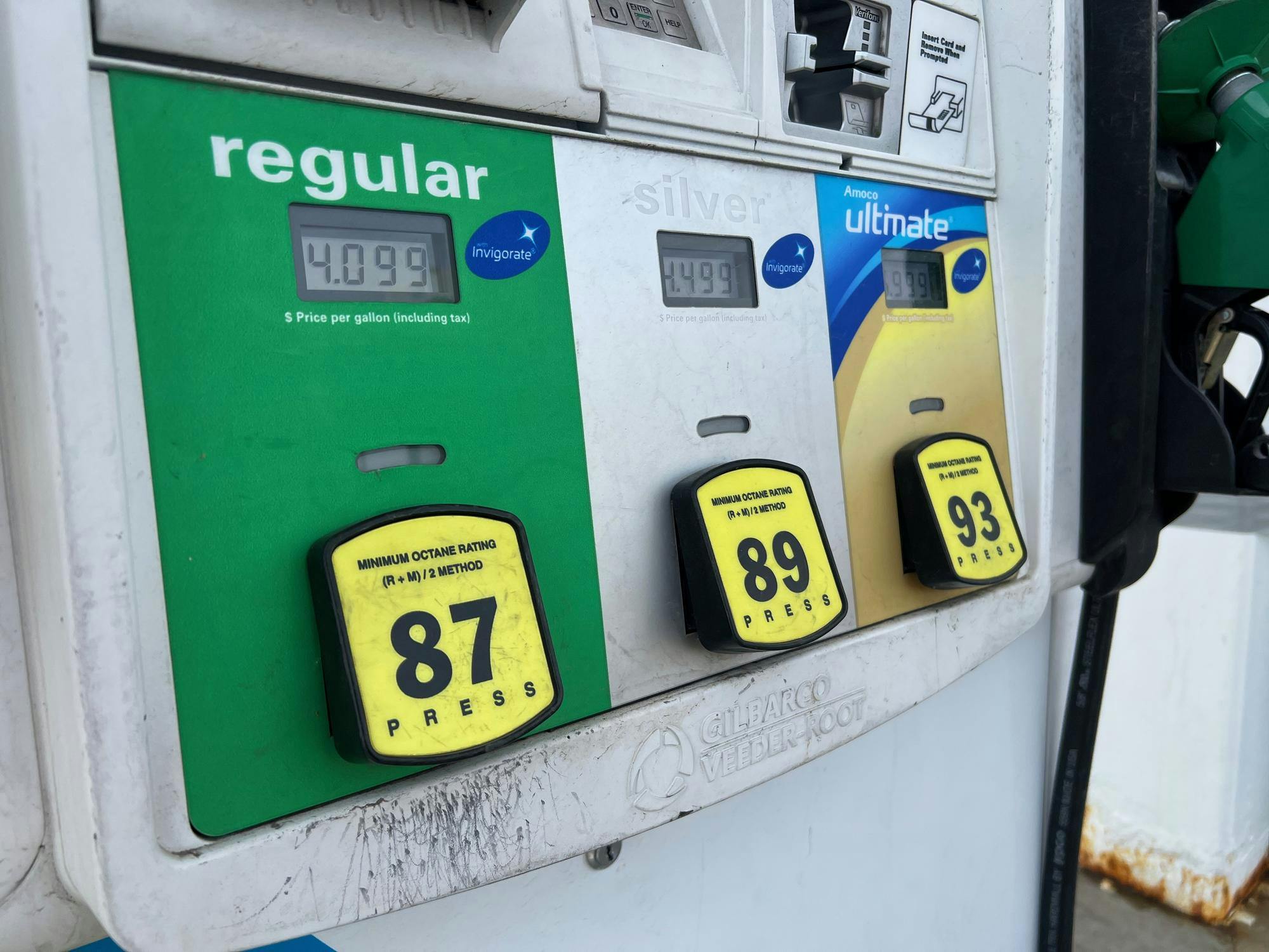 A gas pump shows price per gallon as $4.099 for regular fuel.