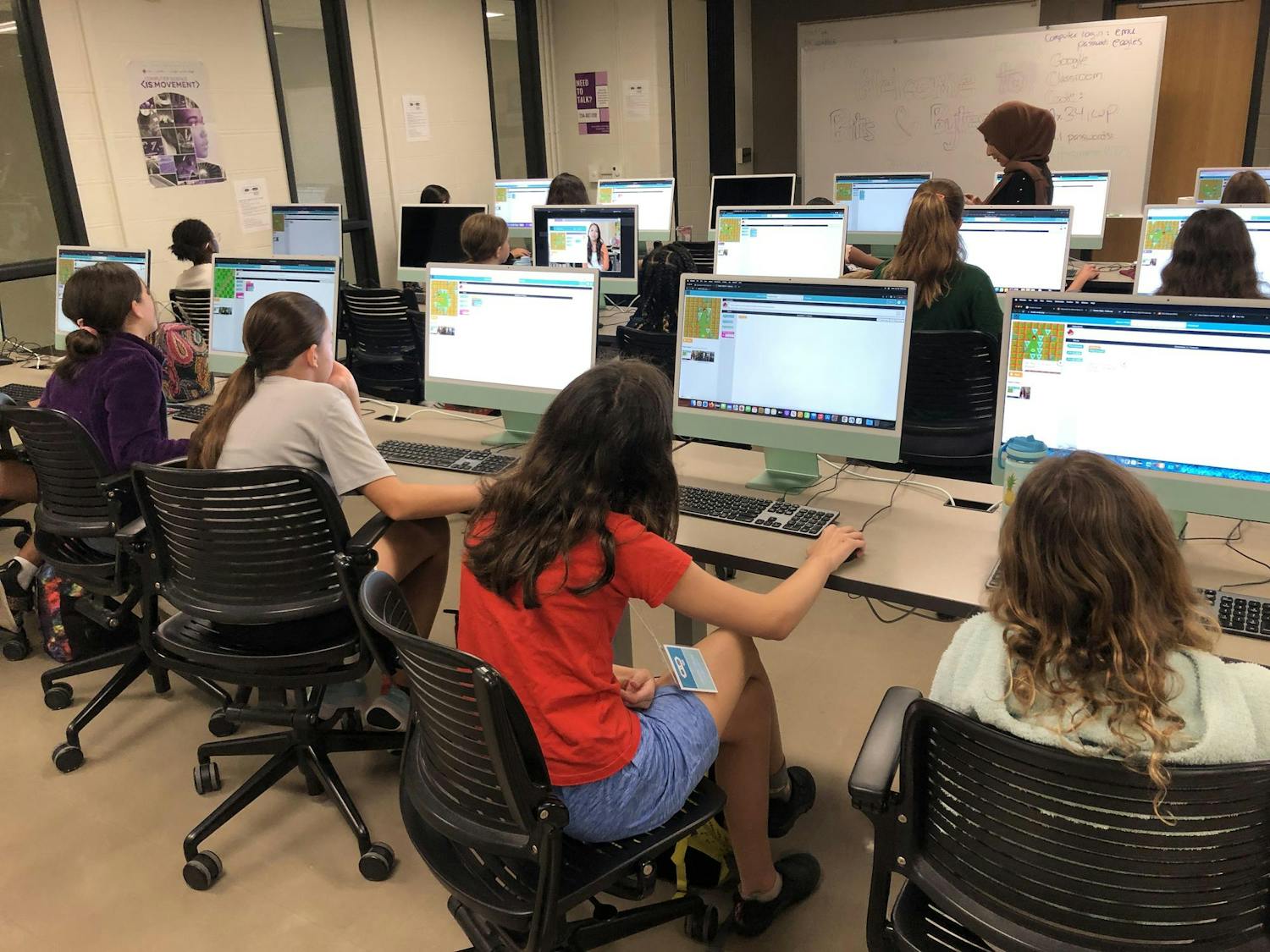 Three rows of middle school students working on a coding project at desktop computers.