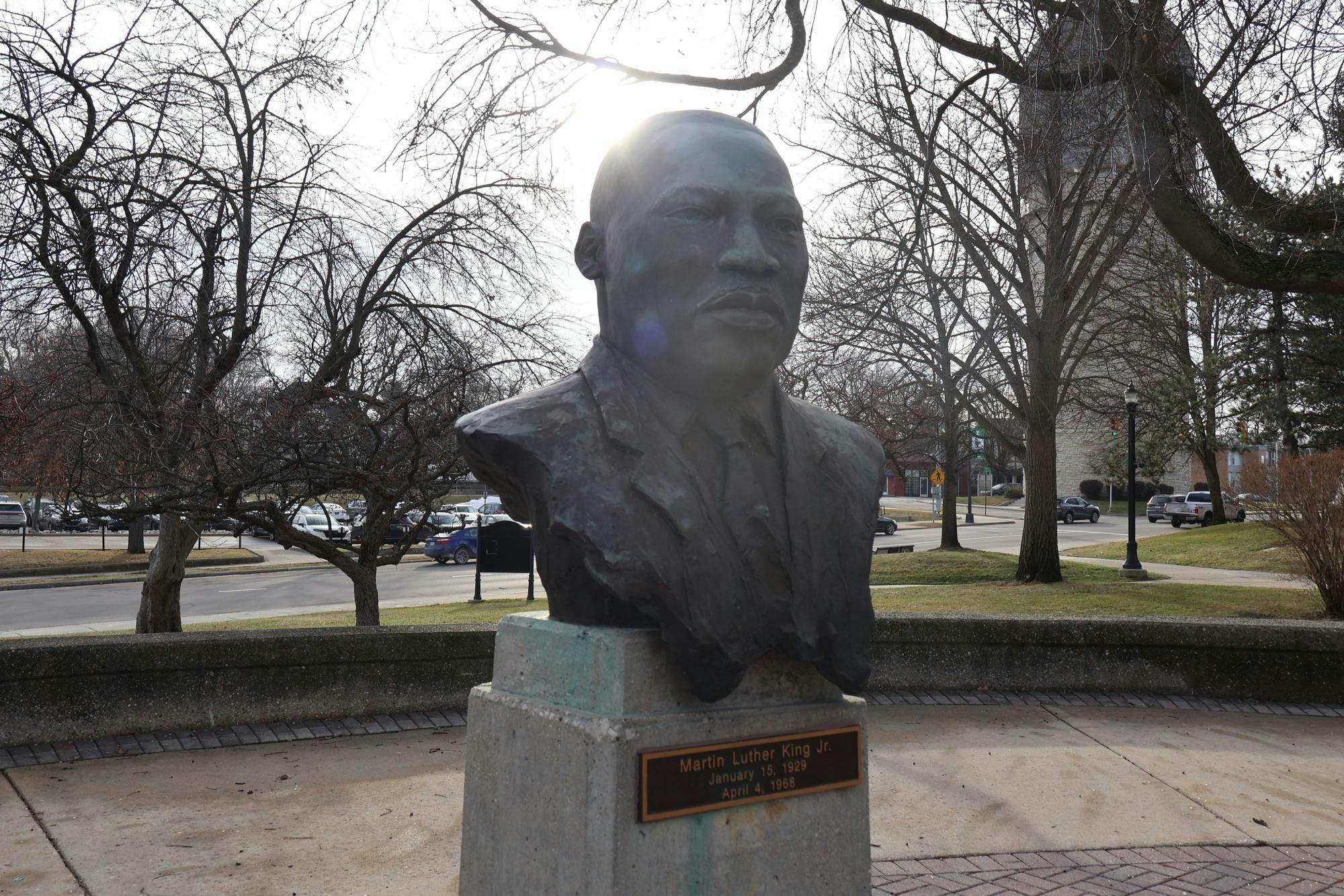A brown, metal bust of Martin Luther King Jr. with an Ypsilanti street and water tower in the background.