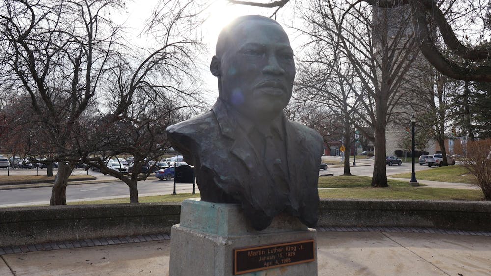 A brown, metal bust of Martin Luther King Jr. with an Ypsilanti street and water tower in the background.