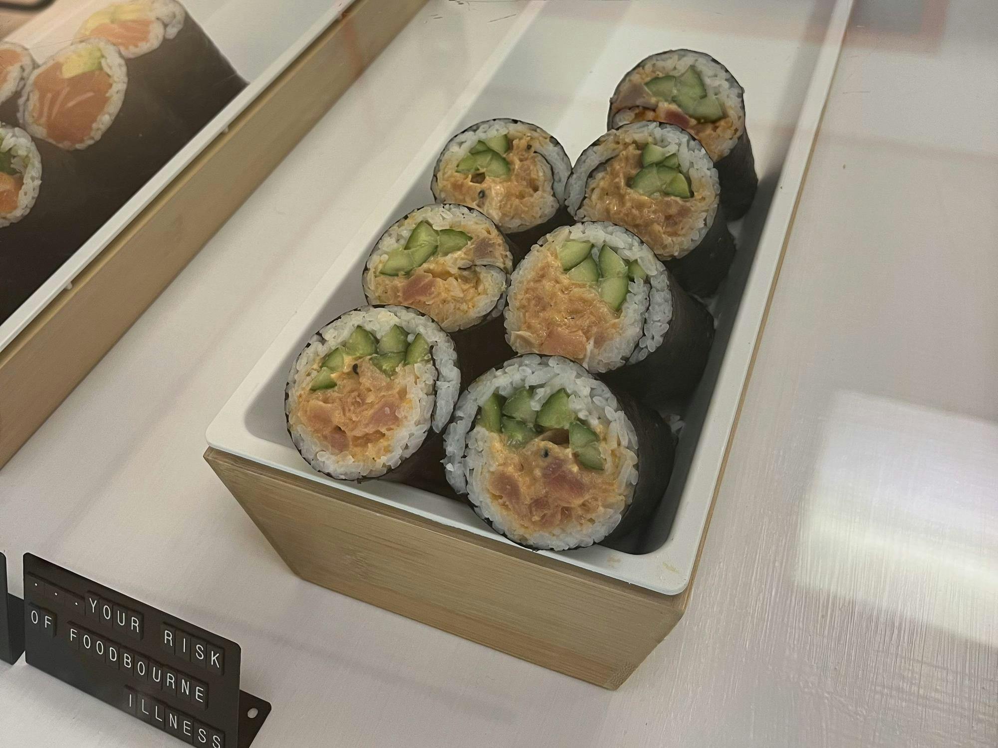 A sushi roll containing fish, cucumber, rice and nori is displayed at a restaurant.