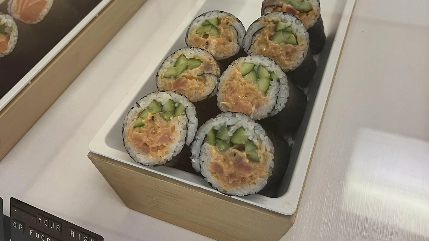 A sushi roll containing fish, cucumber, rice and nori is displayed at a restaurant.