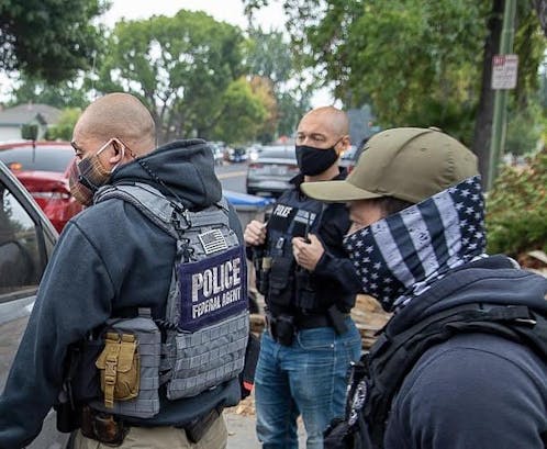 Close-up of three Immigration and Customs Enforcement agents wearing masks to conceal their identities.