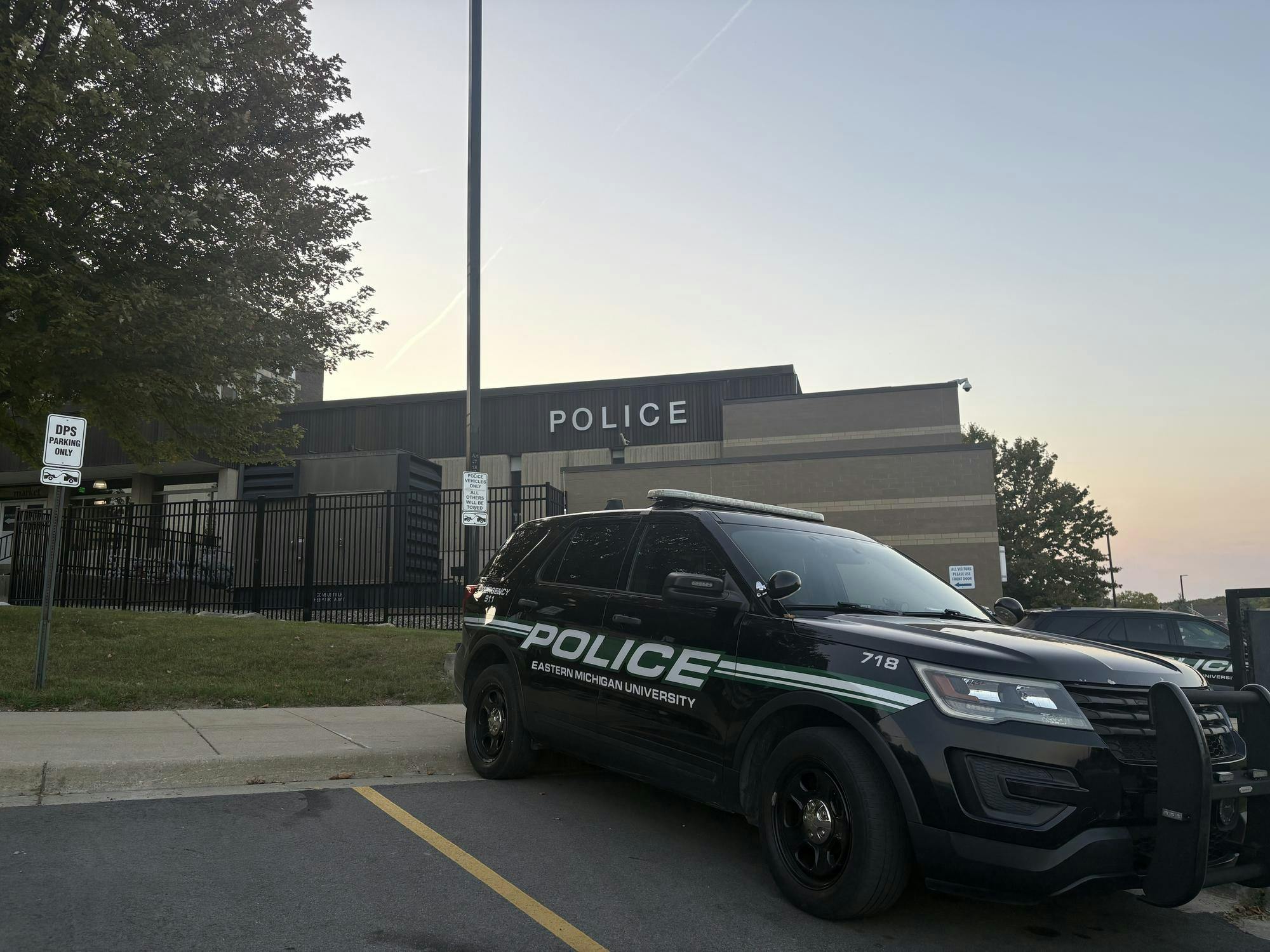 An EMU police car is parked in front of the campus police department.