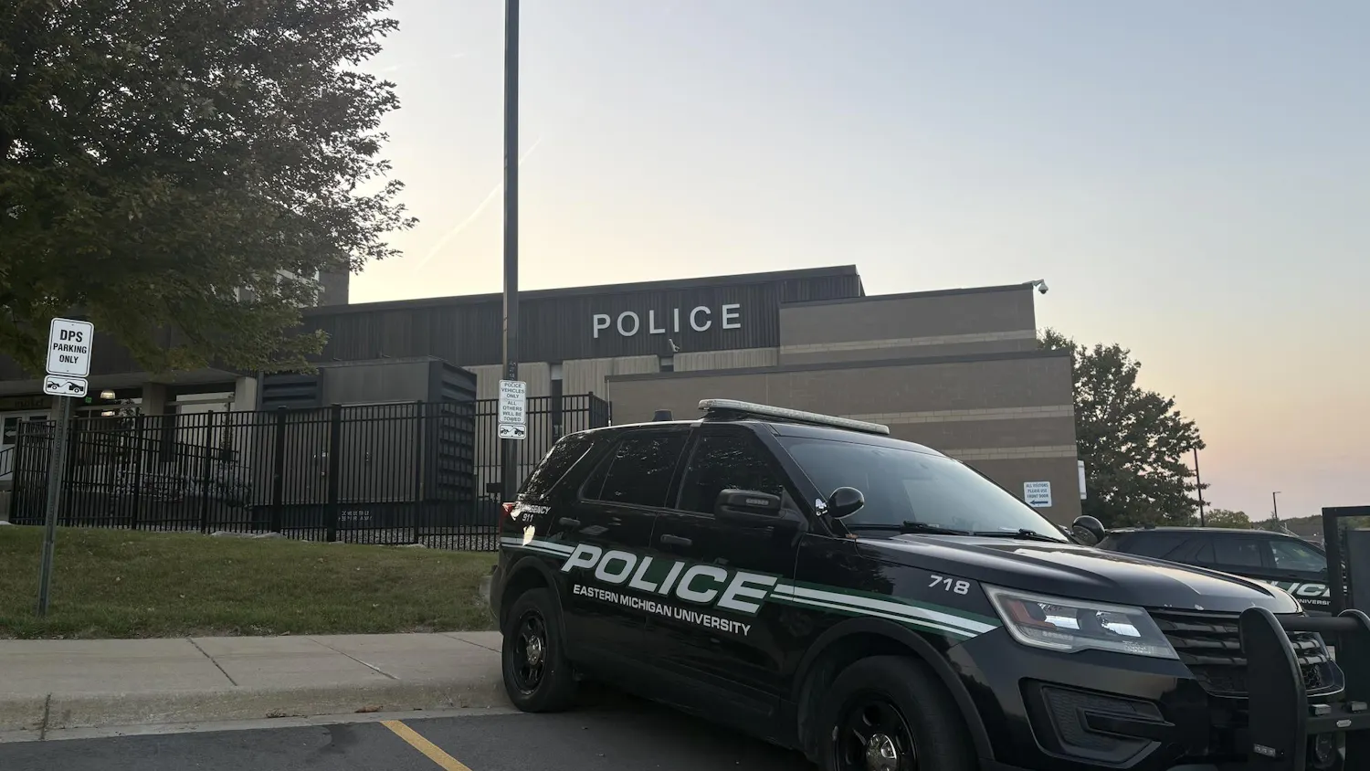 An EMU police car is parked in front of the campus police department.