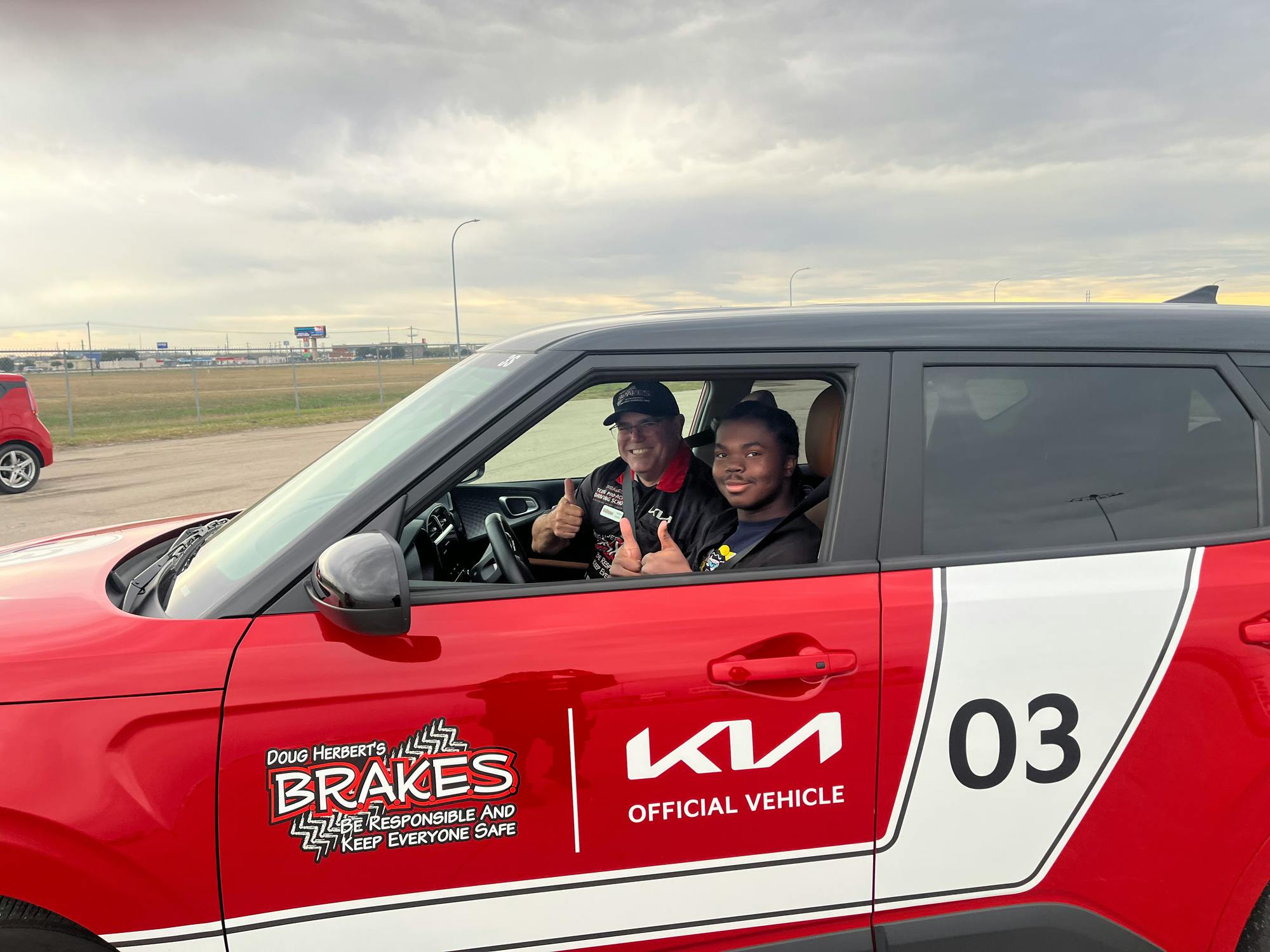 A student and instructor giving a thumbs up in a training car.