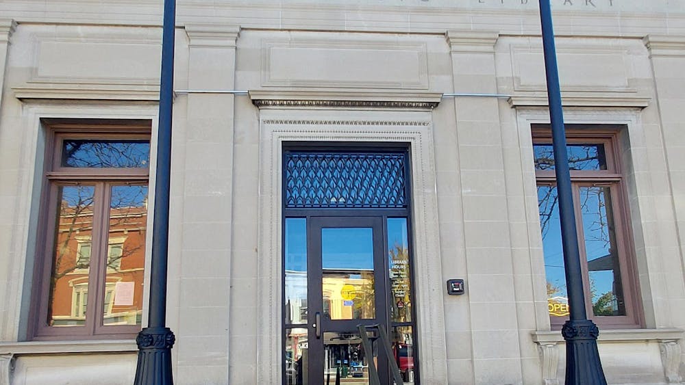 In downtown Ypsilanti, the front entrance of the Ypsilanti Public Library, located on Michigan Avenue, features a glass door and large rectangular windows on both sides.