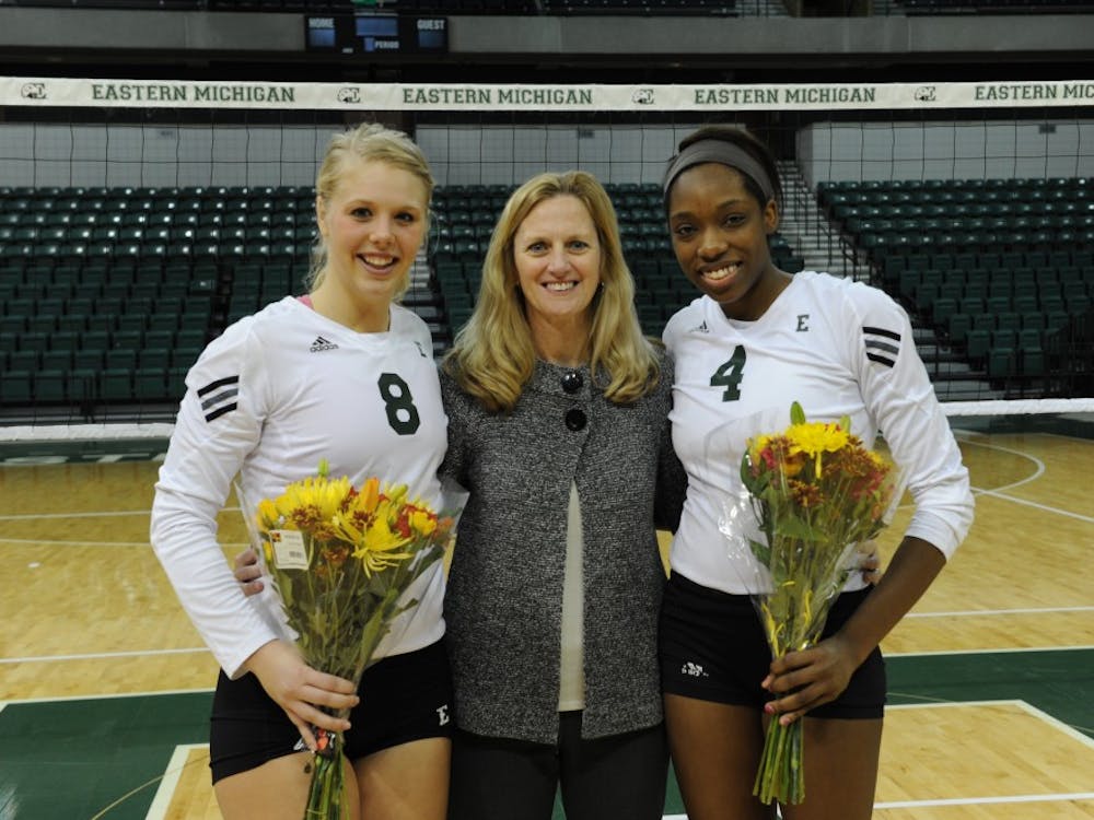 	Seniors Paige Roback (8) and Erin Short (4) pose for a photo with volleyball coach Kim Berrington