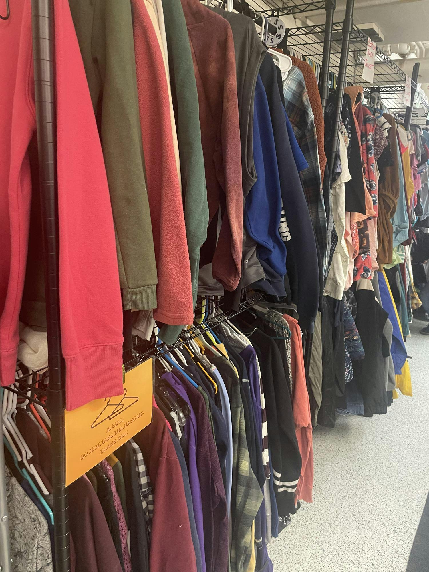 Two stacked clothing racks full of many different styles and colors of clothing.