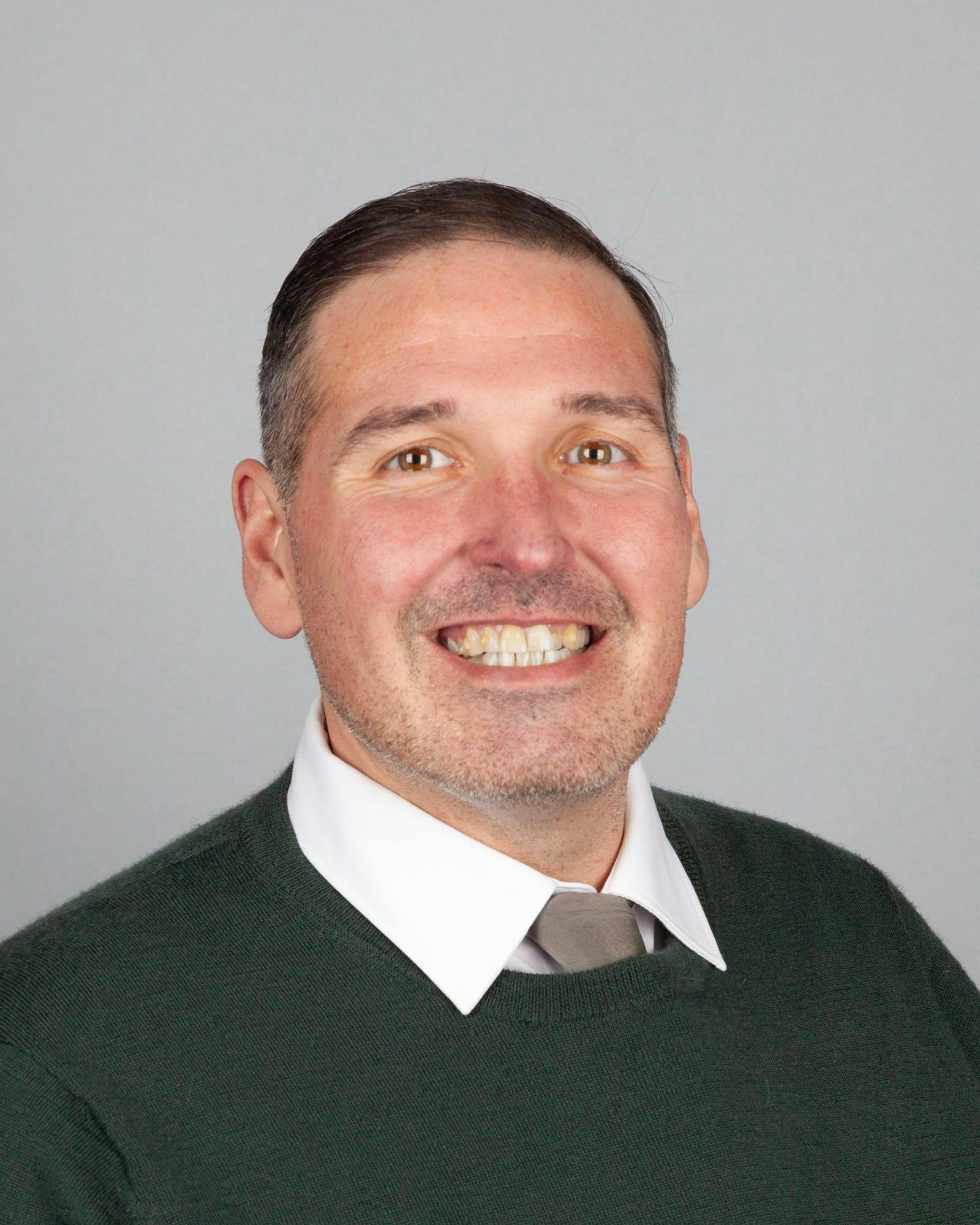 Headshot of Matthew Gregory from the shoulders up, wearing a sweater and white collared shirt.