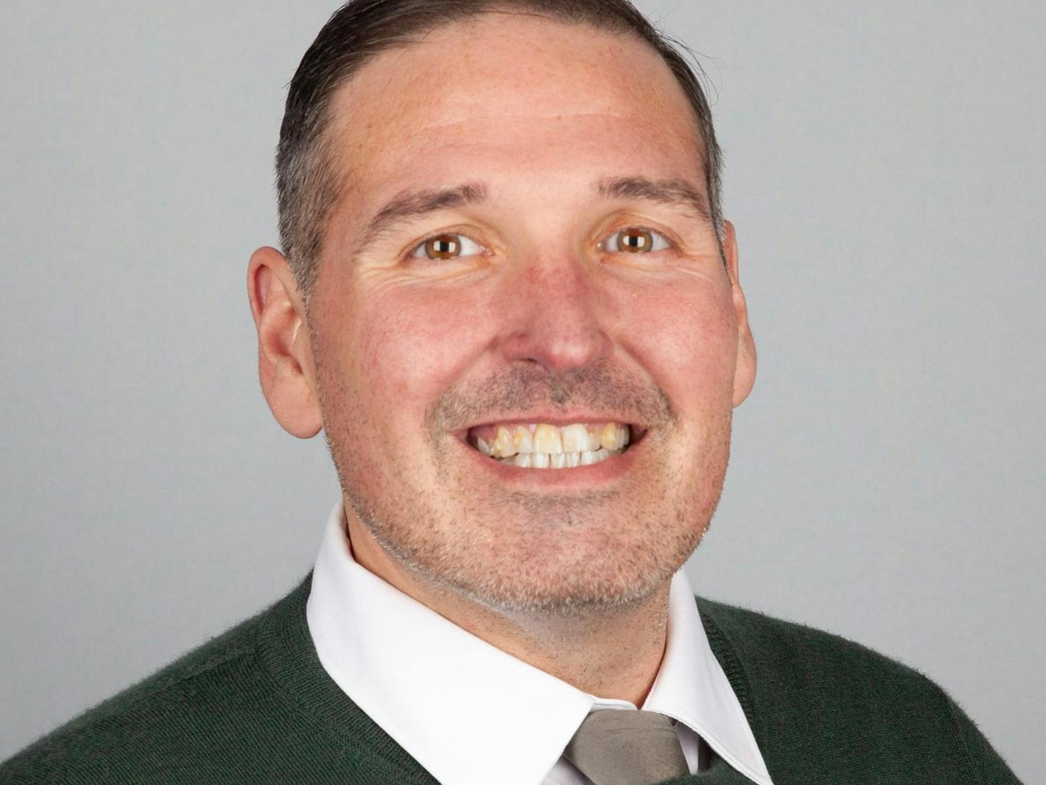Headshot of Matthew Gregory from the shoulders up, wearing a sweater and white collared shirt.