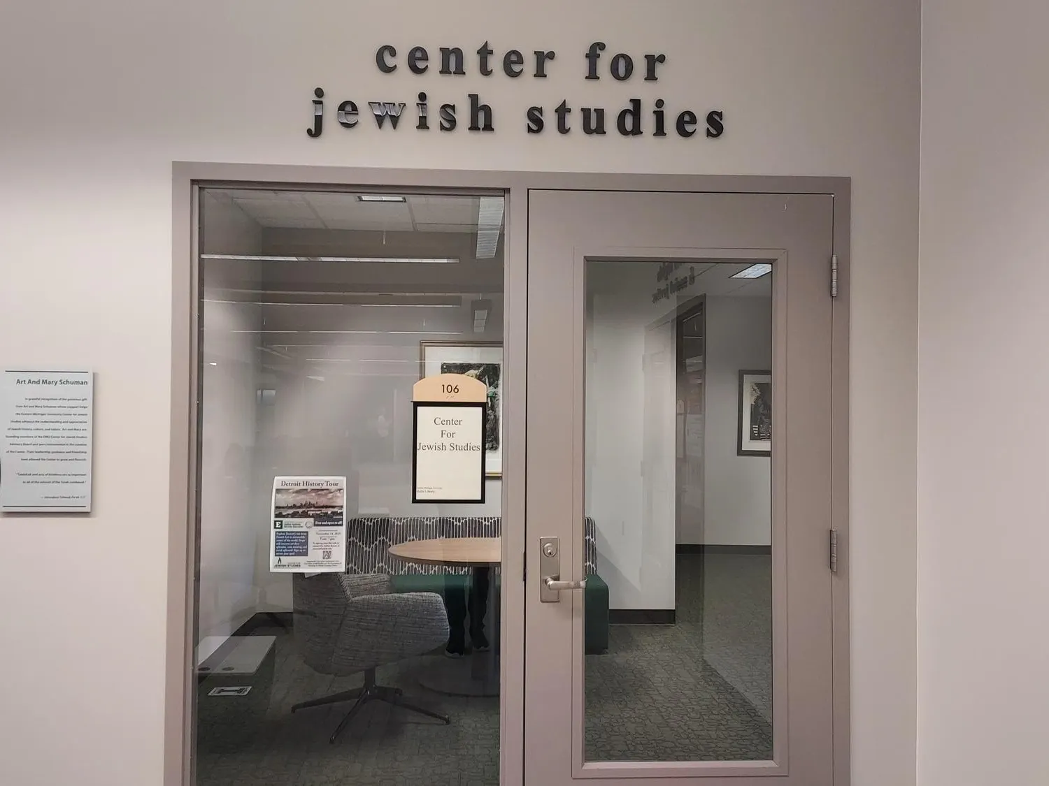At the entrance to the EMU Center for Jewish Studies, there is a glass door that reflects the interior of the center, and letters outline the name above the door.