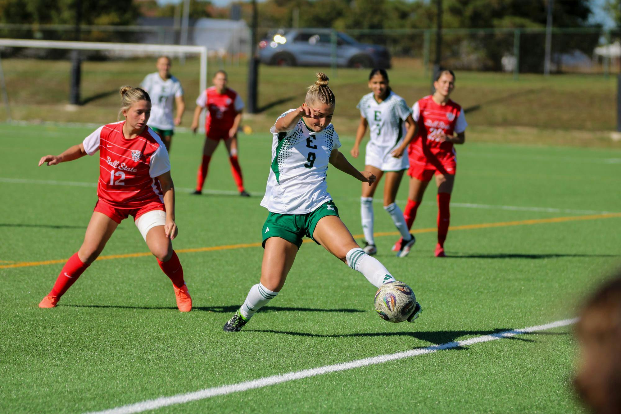 EMU's players in the white jersey, kicking the ball while Ball State player looks to see where it will be kicked, in the red jersey. 