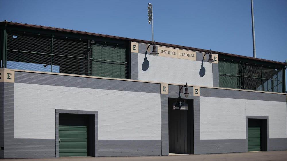 The wall of a baseball stadium from outside. Text in the top center reads "Oestrike Stadium." One entrance is visible with a hanging sign that reads "Center Entrance."