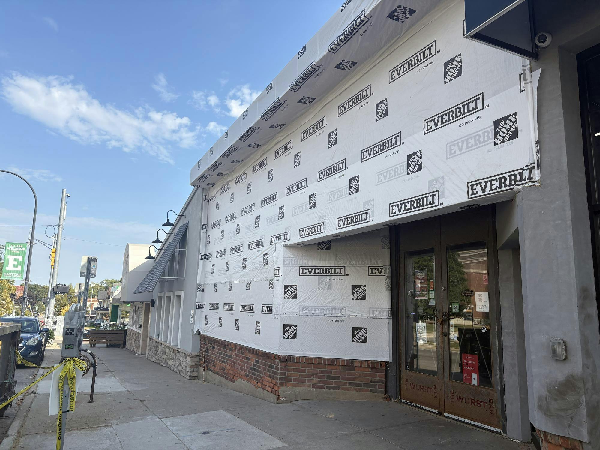 Front of the old Wurst Bar building, now stripped of its siding, is covered in white insulation board and under construction.