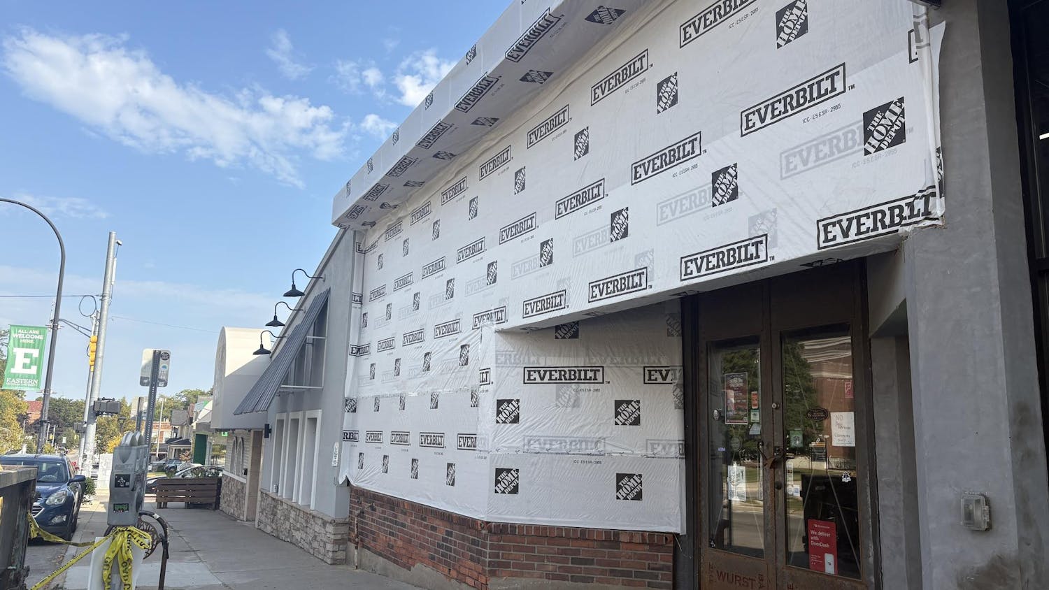 Front of the old Wurst Bar building, now stripped of its siding, is covered in white insulation board and under construction.