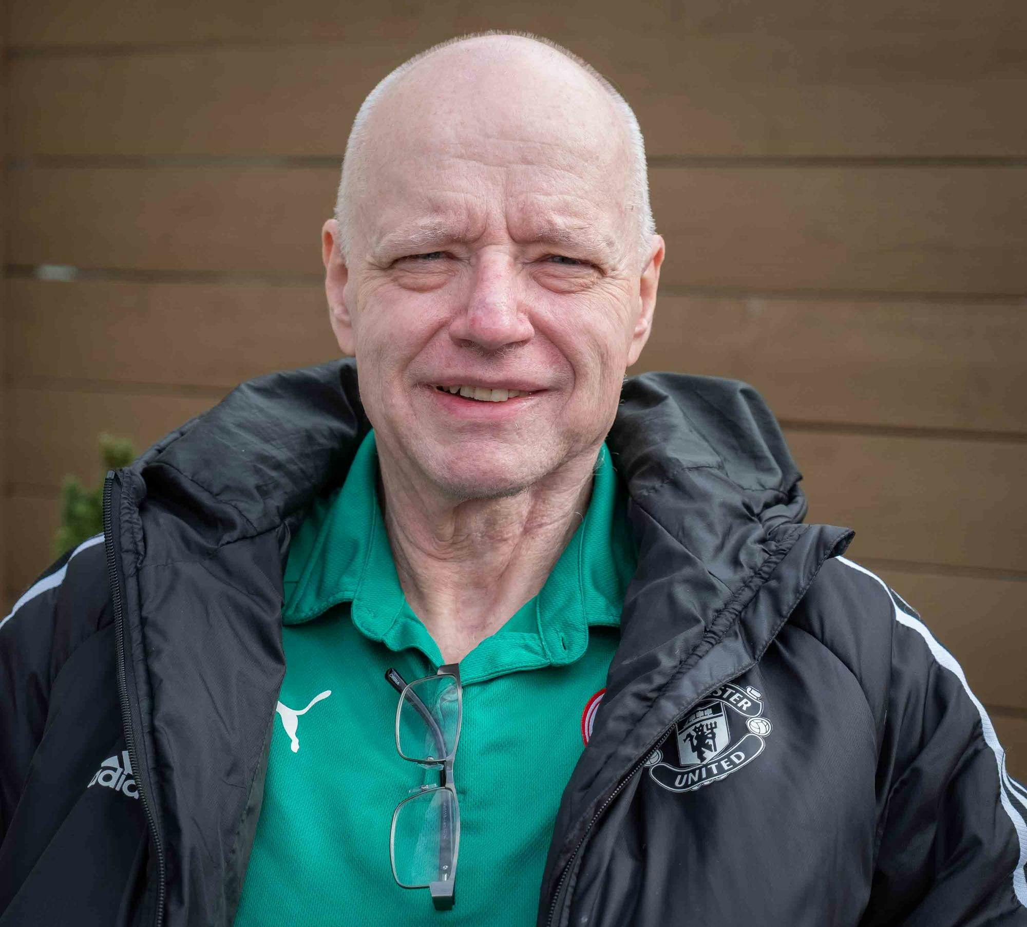 Headshot of Larry O'Connor from the shoulders up, smiling outdoors, wearing a green collared shirt and black windbreaker jacket.