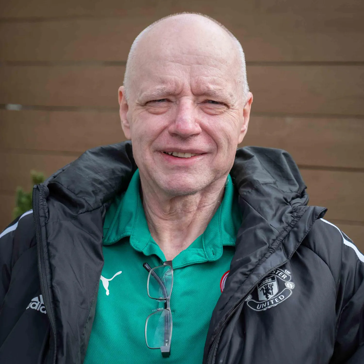 Headshot of Larry O'Connor from the shoulders up, smiling outdoors, wearing a green collared shirt and black windbreaker jacket.