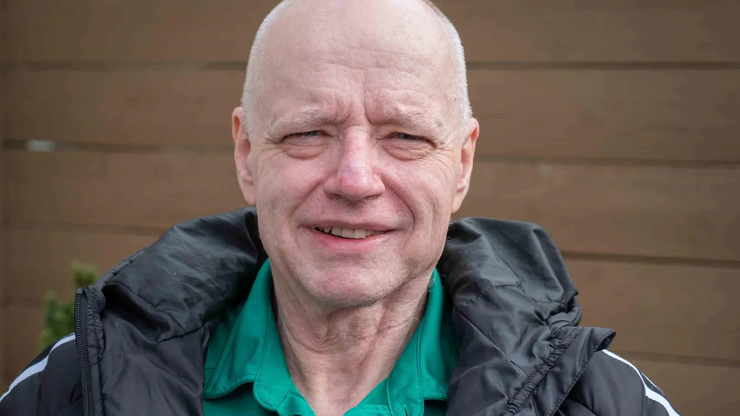 Headshot of Larry O'Connor from the shoulders up, smiling outdoors, wearing a green collared shirt and black windbreaker jacket.