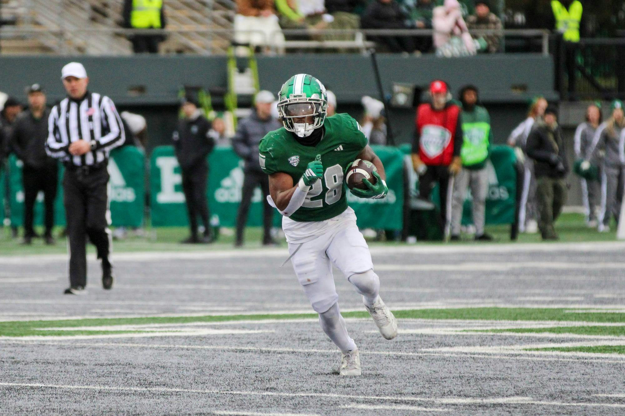#28, in a green jersey, running with the football