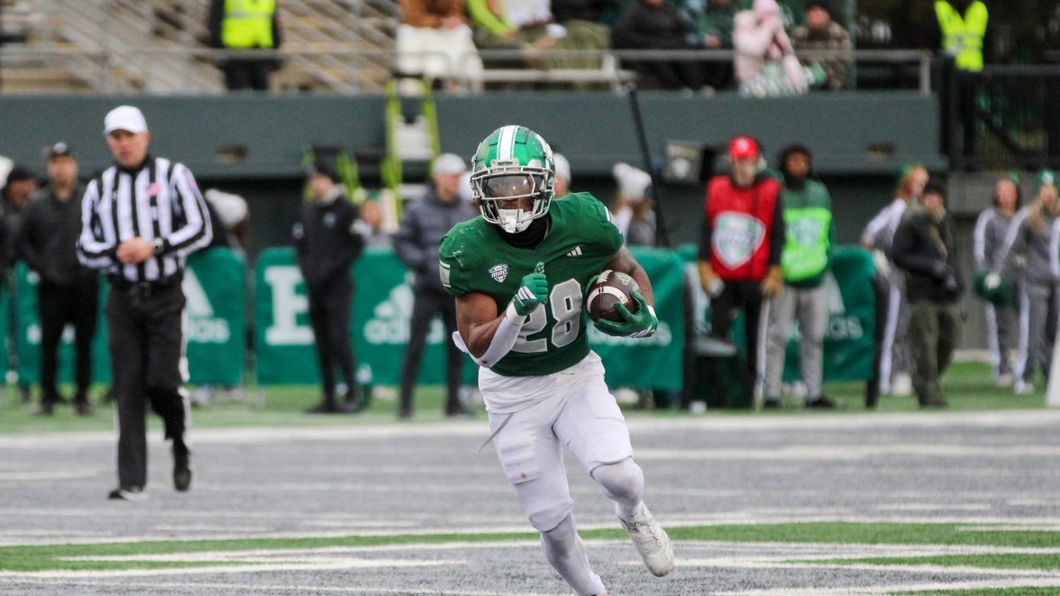 #28, in a green jersey, running with the football