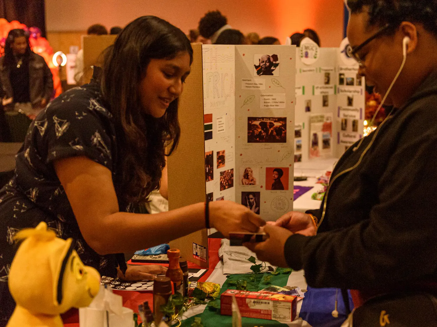 A person behind an event booth places a sticker into another persons booklet.