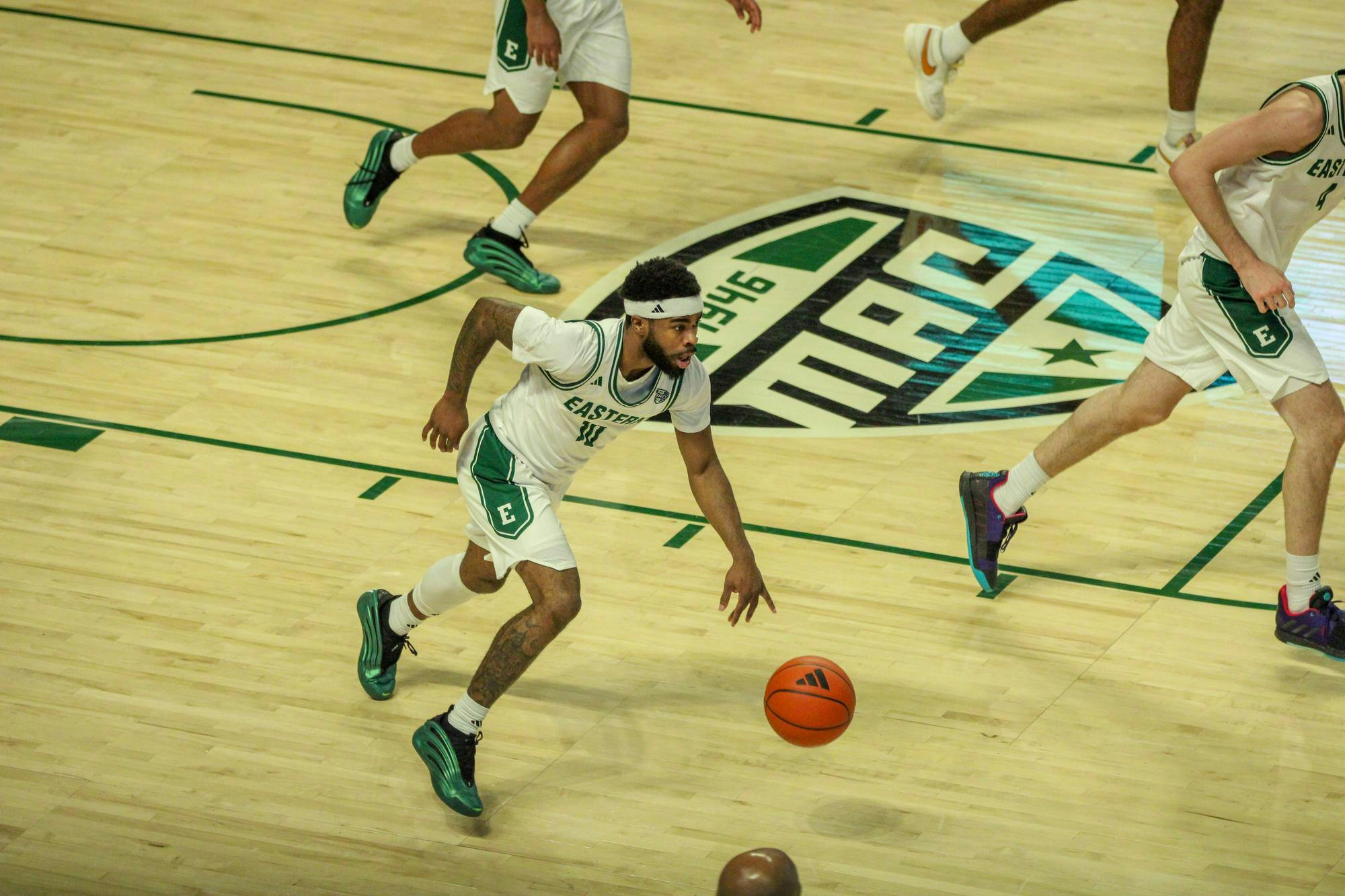 #10, in a white and green jersey, dribbling down the court.