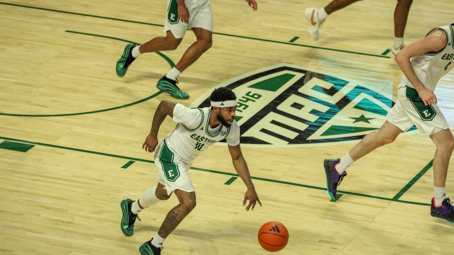#10, in a white and green jersey, dribbling down the court.