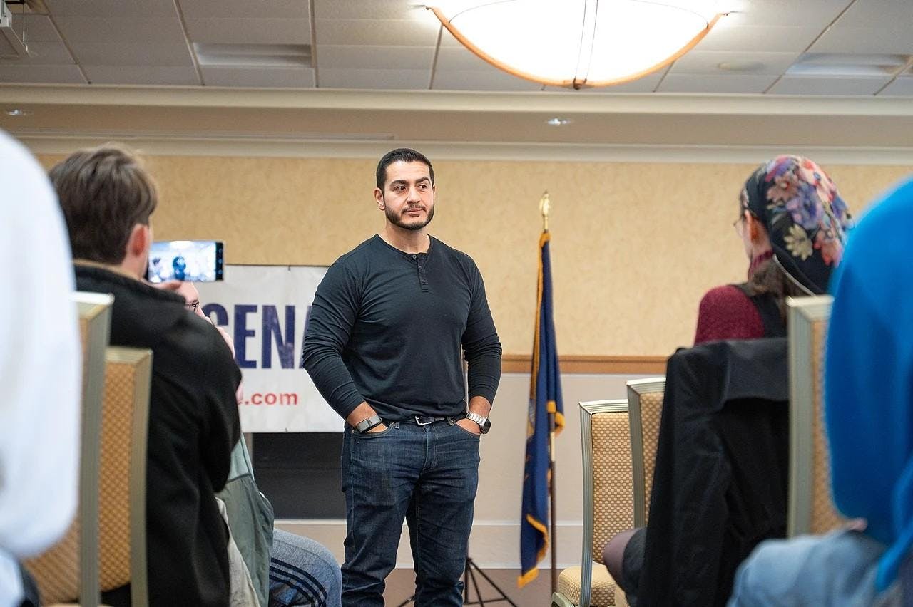 Abdul El-Sayed speaks with attendees, who sit in rows of chairs.