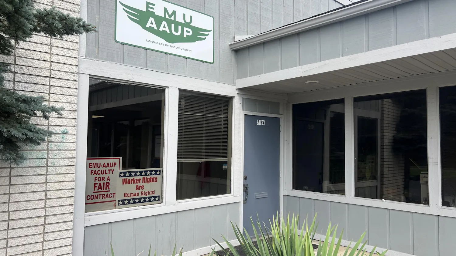 The exterior of the EMU-AAUP office. Two signs can be seen in the window reading "EMU-AAUP faculty for a fair contract" and "Worker rights are human rights!"