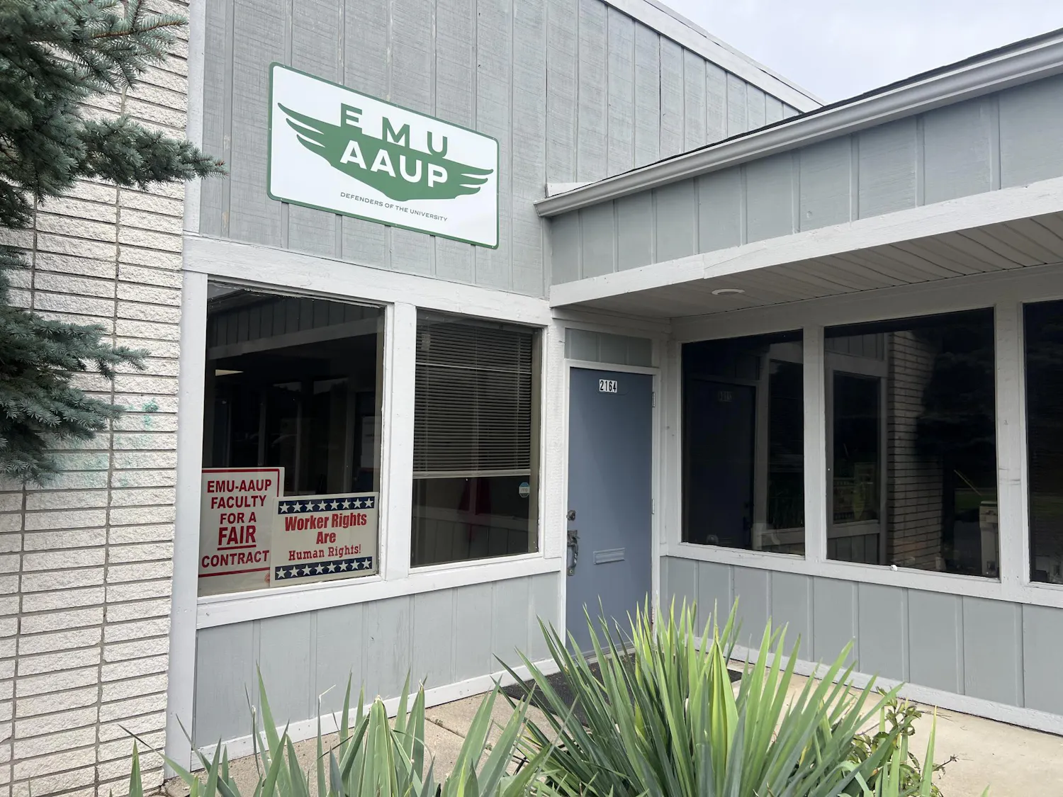 The exterior of the EMU-AAUP office. Two signs can be seen in the window reading "EMU-AAUP faculty for a fair contract" and "Worker rights are human rights!"
