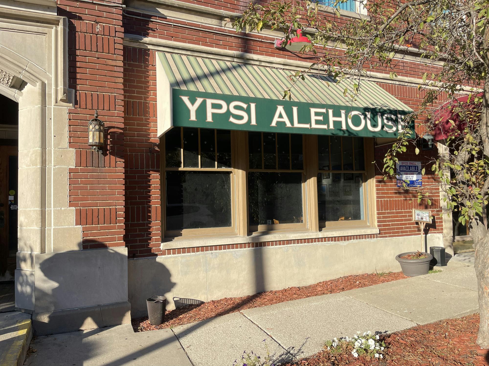 Exterior of a brick building with a green canopy reading "Ypsi Alehouse."