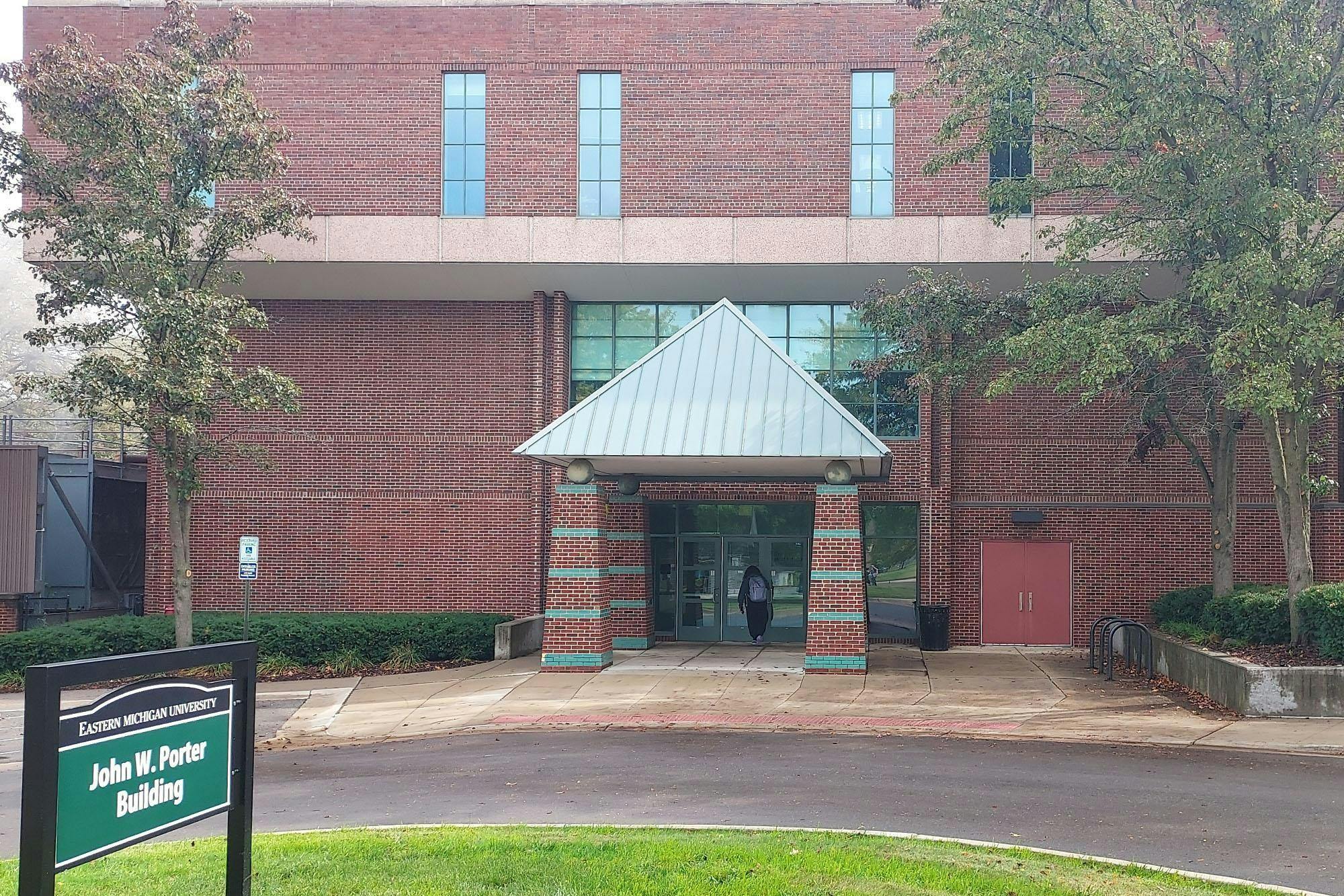 Red brick building with a driveway in front. Green sign to the left reads "John W. Porter Building."