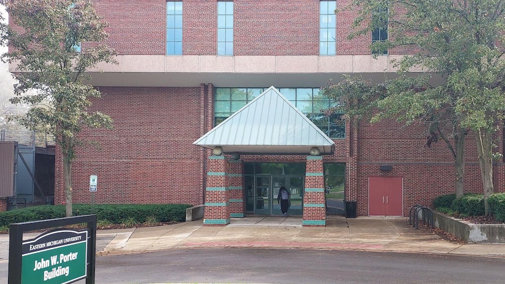 Red brick building with a driveway in front. Green sign to the left reads "John W. Porter Building."