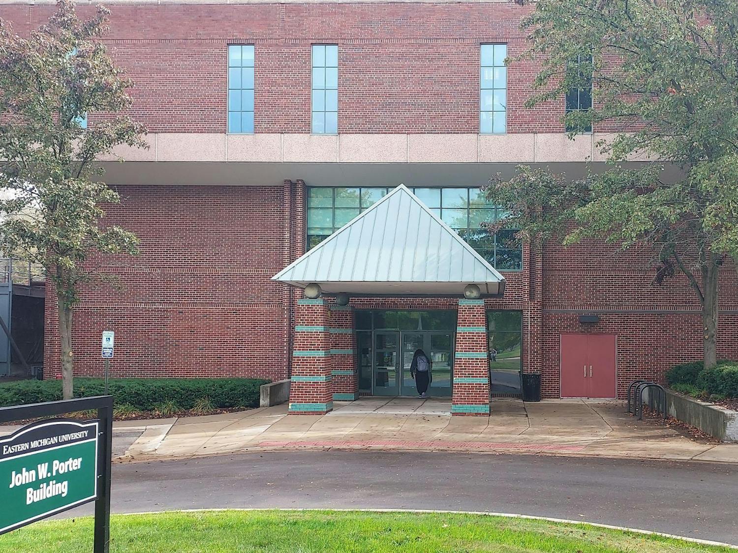 Red brick building with a driveway in front. Green sign to the left reads "John W. Porter Building."