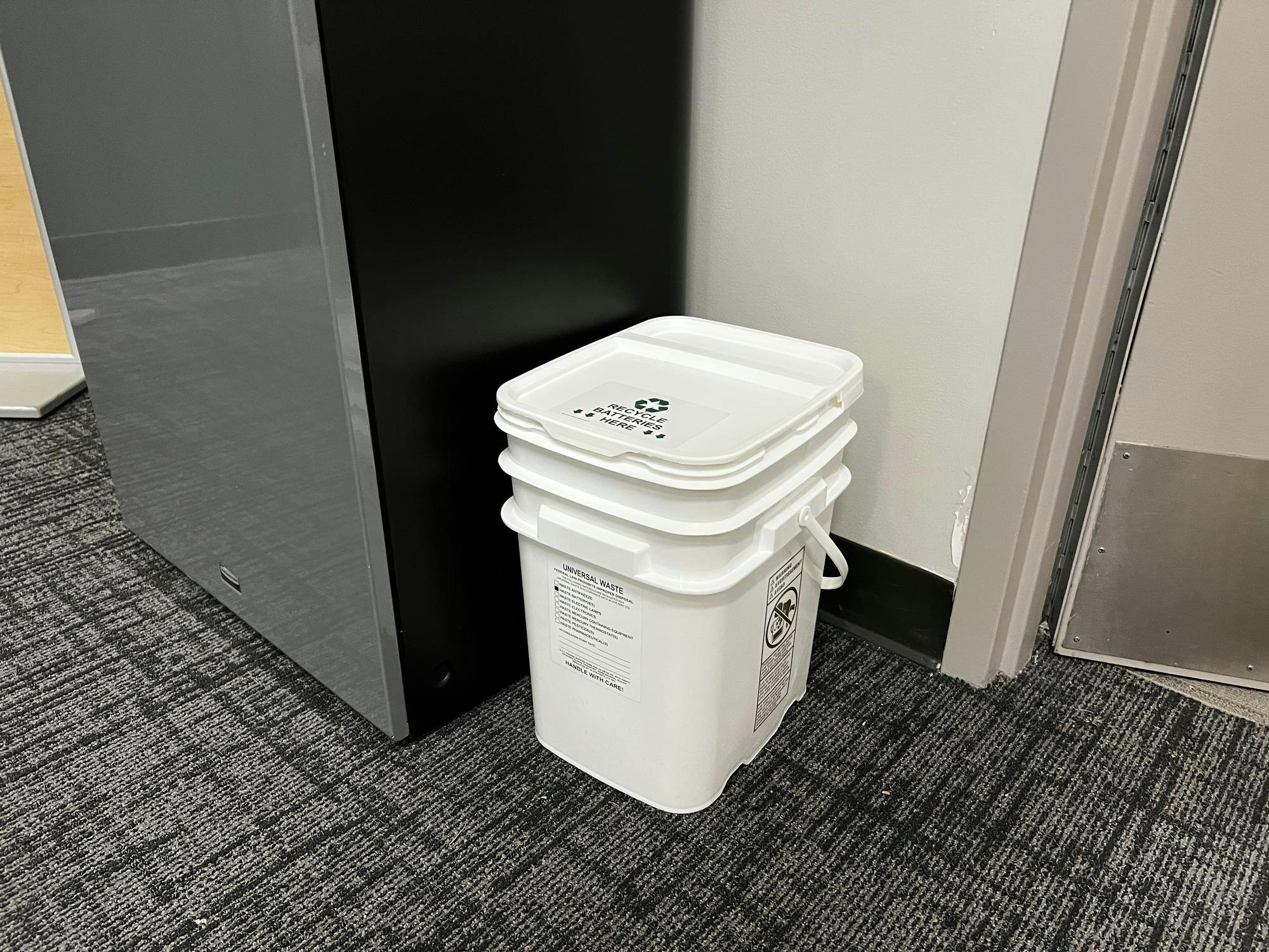 A small white plastic box that says "recycle batteries here" in black letters.