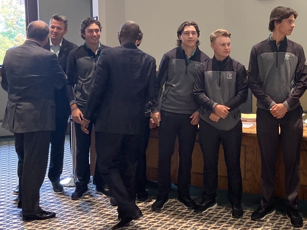 Smith and Simpson shake hands with student athletes