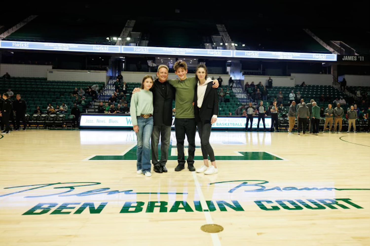 Ben Braun's family, including his wife, Jessica, their son Julius, and their daughter Eliza, stand at center court Saturday, Nov. 18, 2023, as Eastern Michigan University celebrates the naming of the court in honor of the legendary coach.