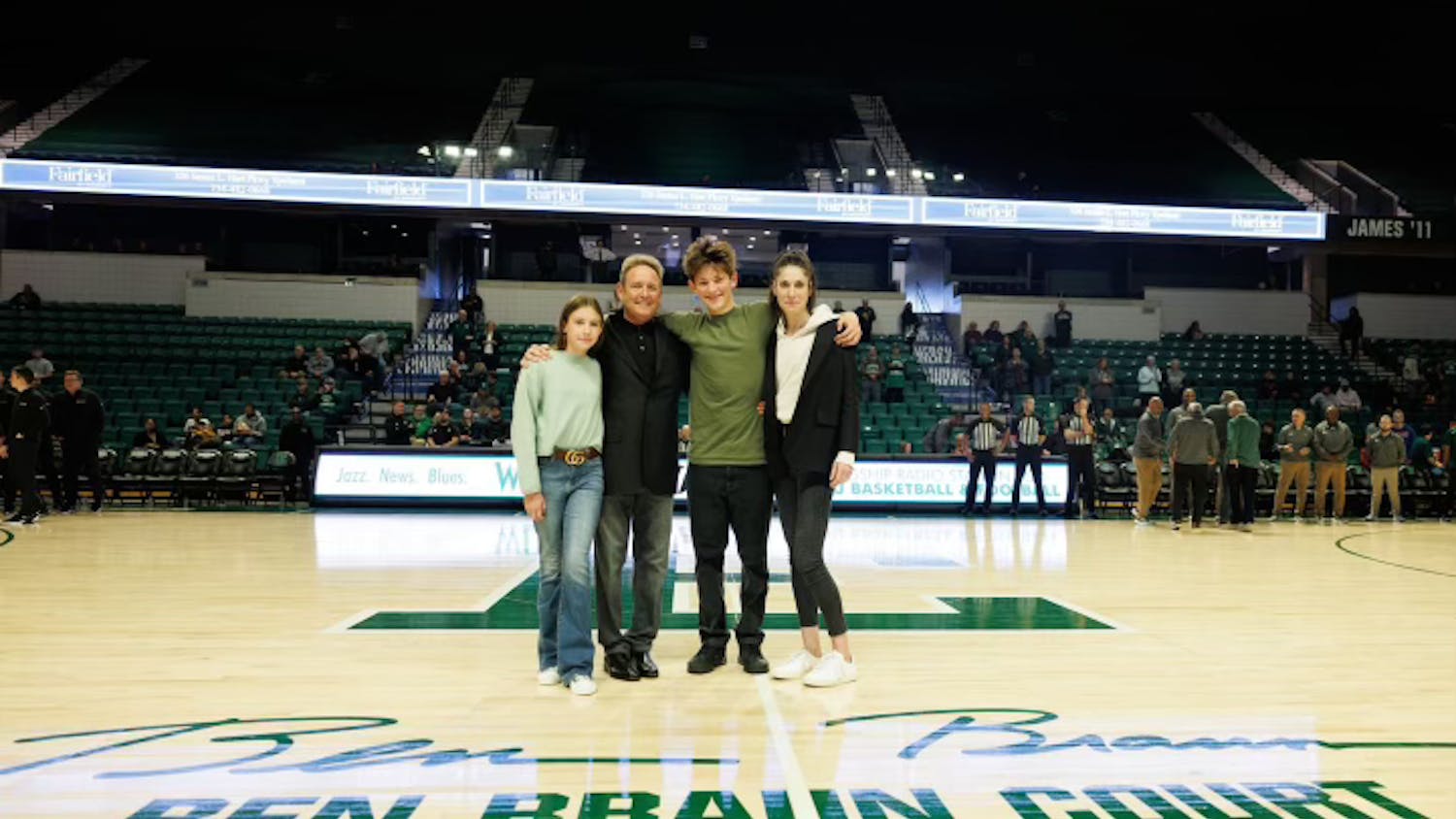 Ben Braun's family, including his wife, Jessica, their son Julius, and their daughter Eliza, stand at center court Saturday, Nov. 18, 2023, as Eastern Michigan University celebrates the naming of the court in honor of the legendary coach.
