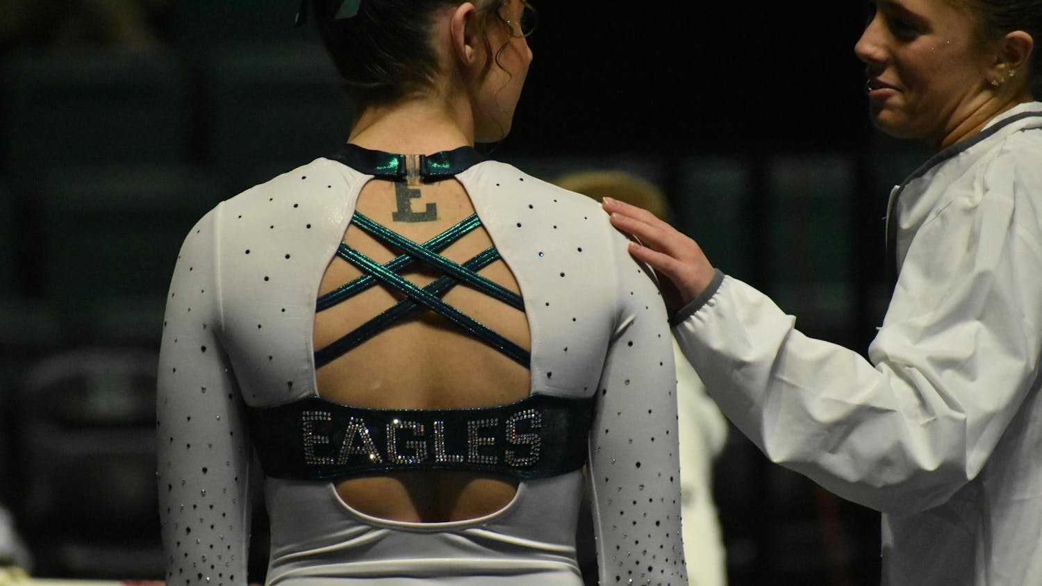 Gymnast Analiah Solorio faces away from the camera as she speaks with teammate Kyrie Lowe.