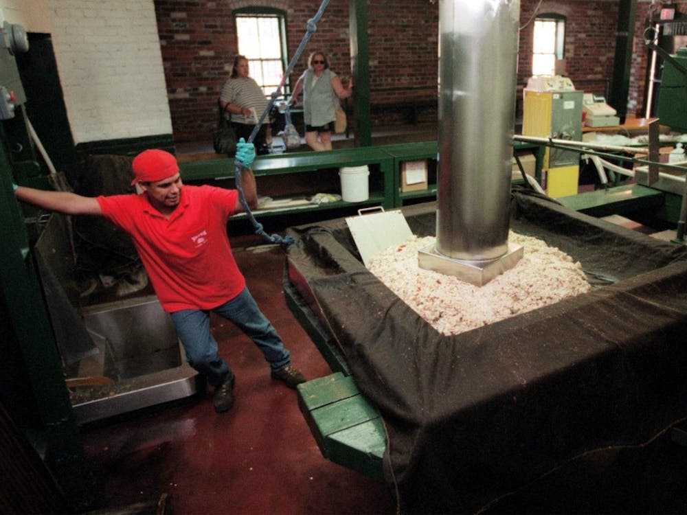 George Salazar, an employee of Yates Cider Mill in Rochester, Michigan distributes chopped apple mash into the cider press.