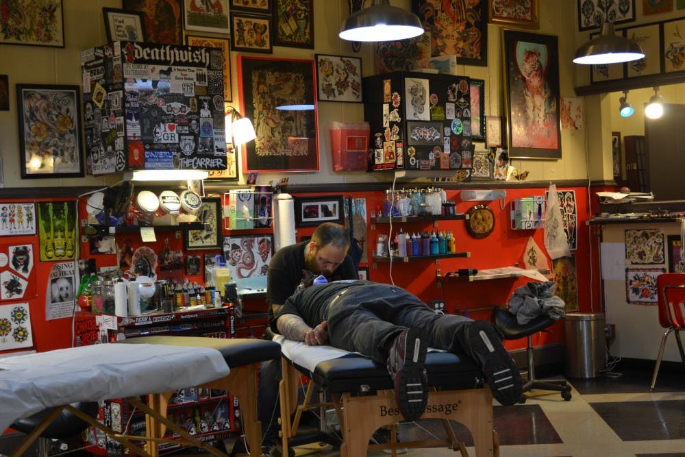 Chris concentrating on his customer who's receiving a painful head tattoo.