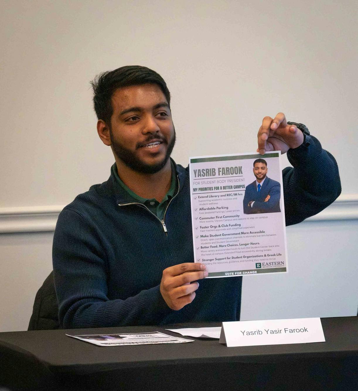 Yasrib Farook holds a flyer that says, "Yasrib Farook for Student Body President," and has a bulleted list under the title, "My Priorities for a Better Campus."
