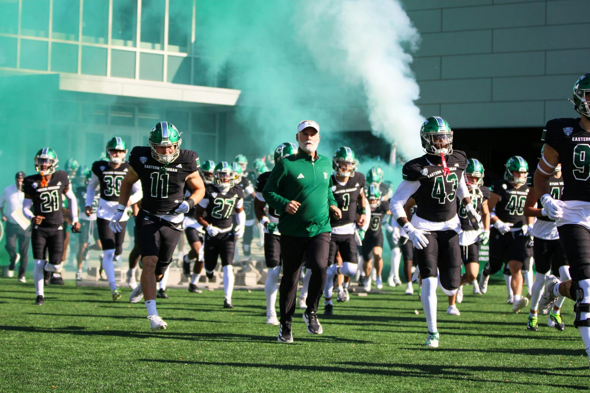 Chris Creighton, dressed in green, running with his team, who are wearing black jerseys