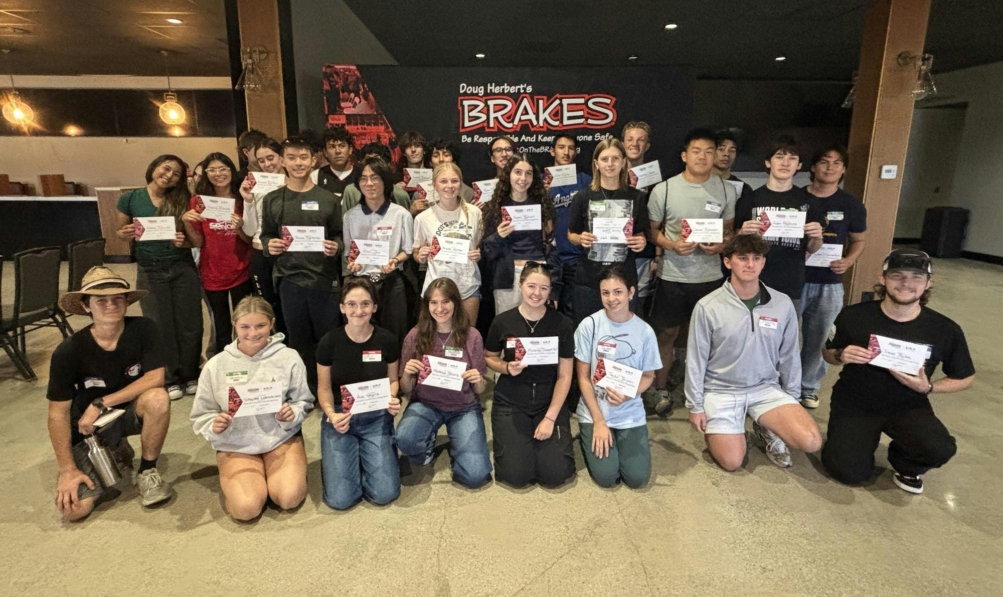 A group of students smiling while holding up certificates.