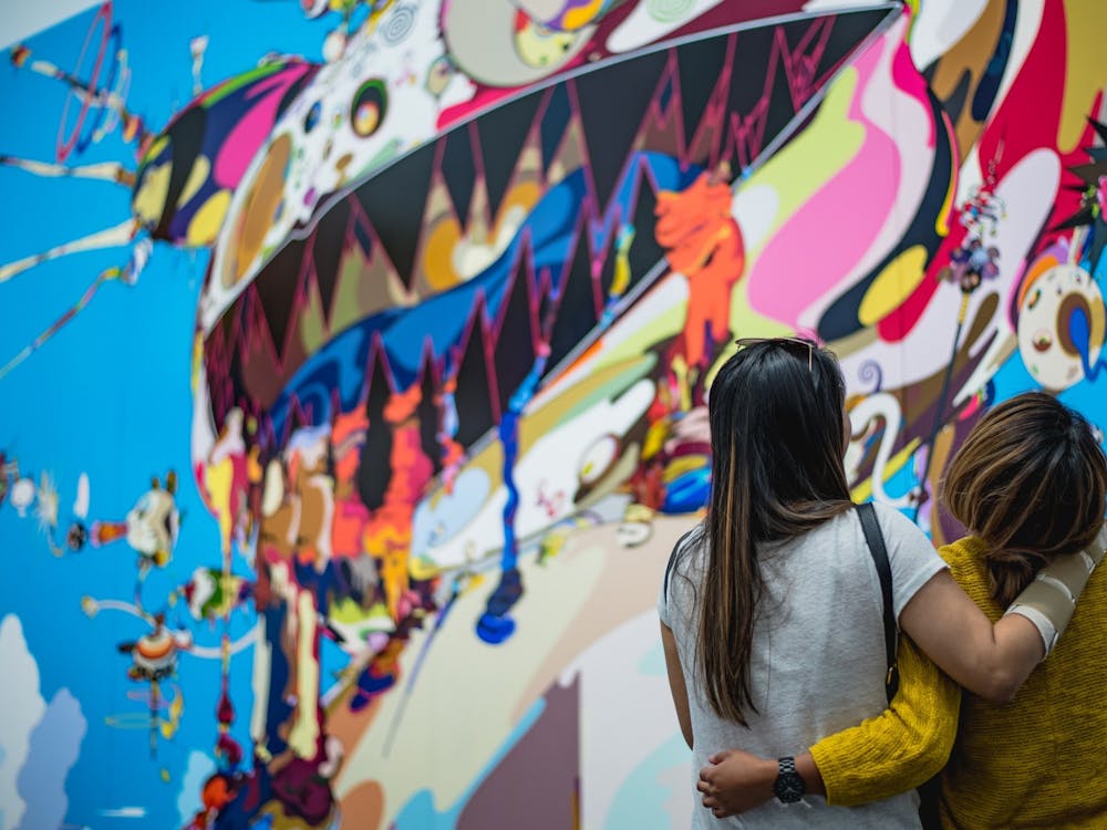 Two friends, arm in arm, looking at street art. Photo by Chris Palomar on Unsplash