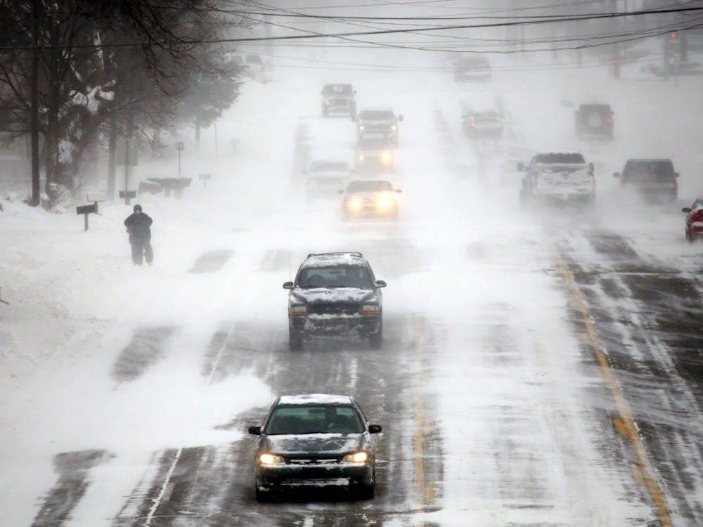 A person struggles to walk in the strong wind gusts, as vehicles pass on Bristol Road in Burton, Mich., on Monday Jan. 6, 2014. (Ryan Garza/Detroit Free Press/MCT)